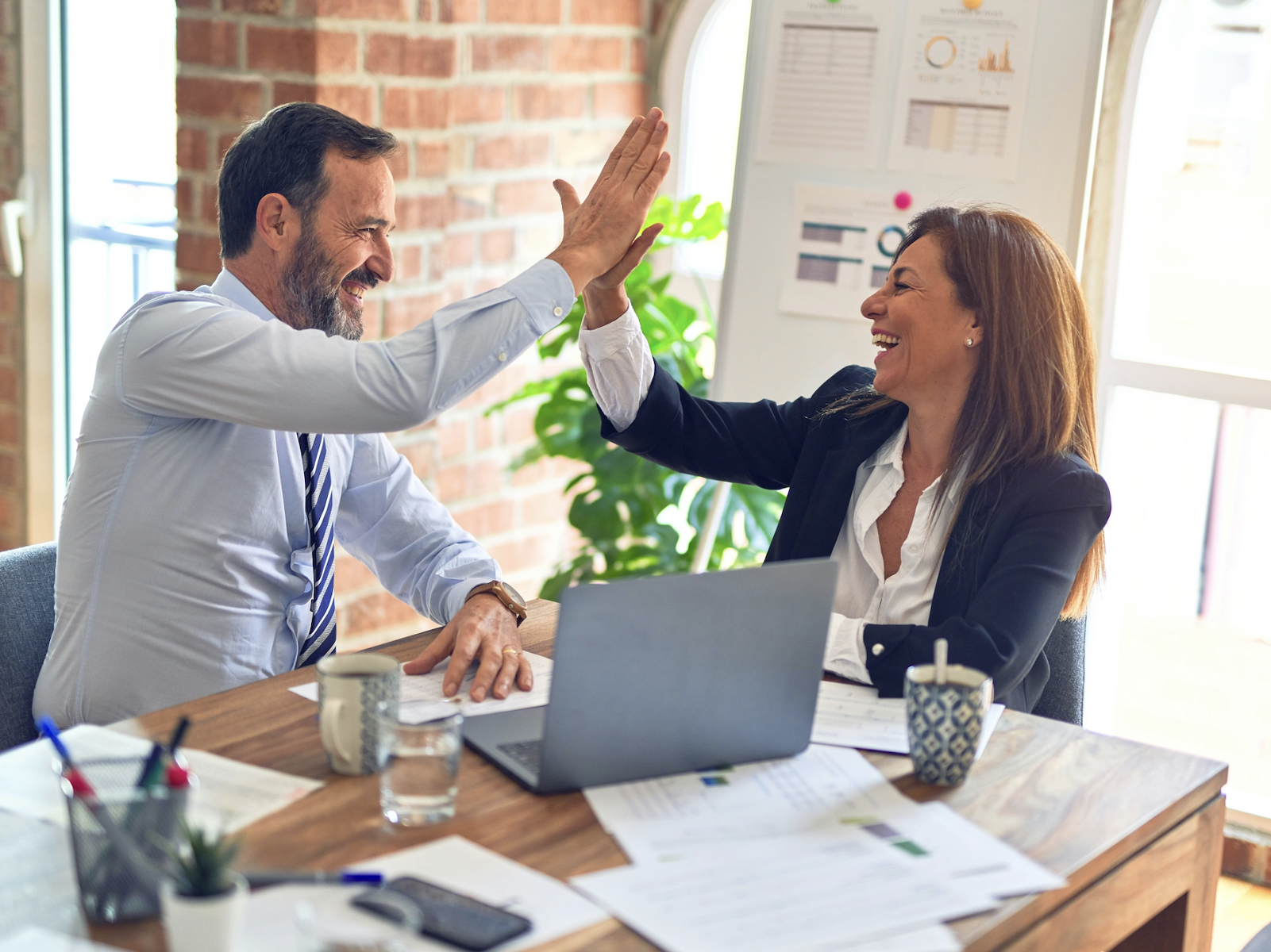man and woman giving each a high five after closing a sale