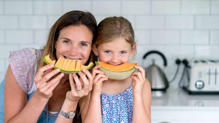 mom and daughter eating slices of cantaloupe