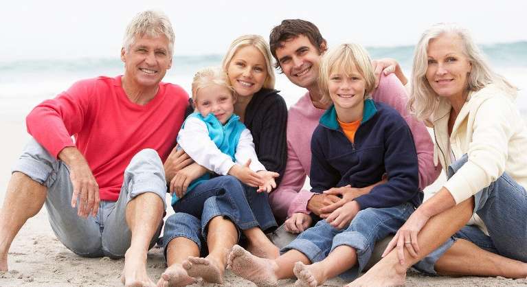 multi generational family smiling on beach