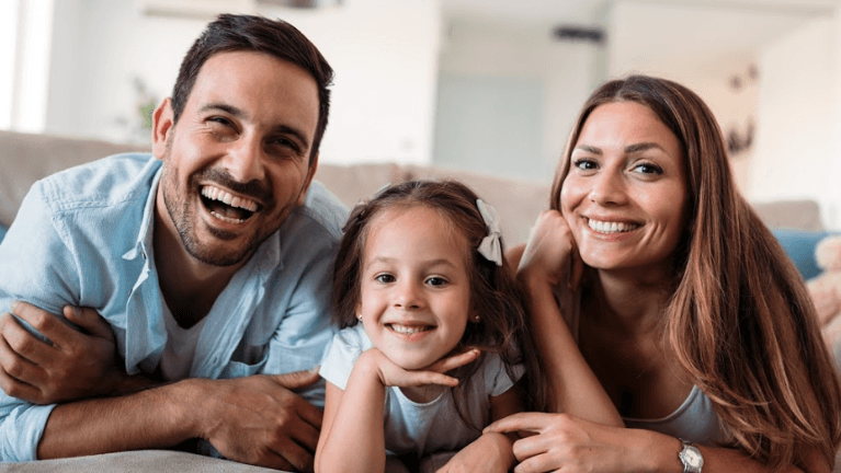 mother, daughter, and father smiling 