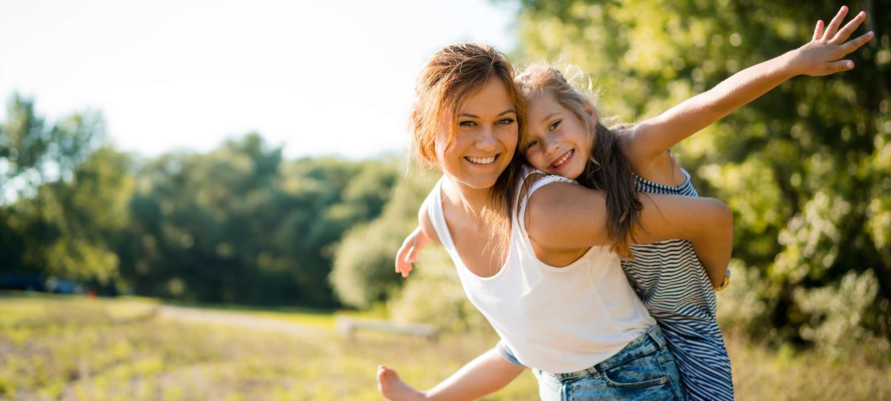 young girl and her mom smiling in a field